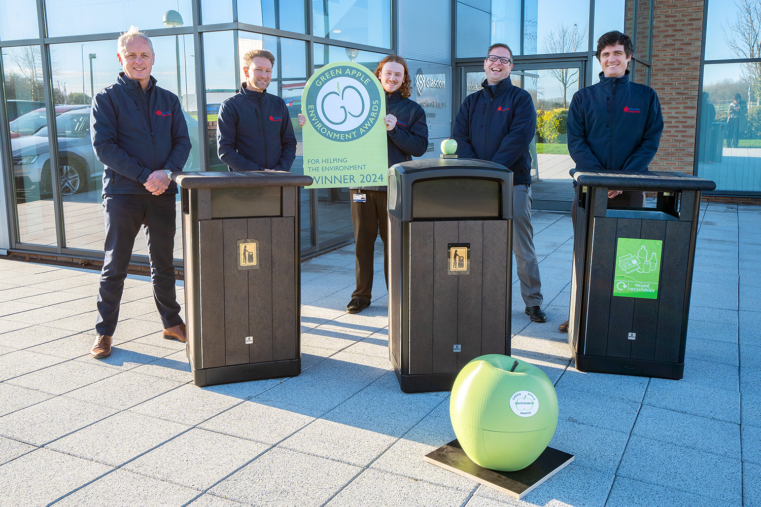 design team with green apple award and origin bins