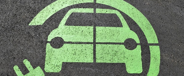 A green electric charging symbol on concrete