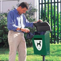 Man disposing of a dog poop bag in the Fido Pet Waste Station